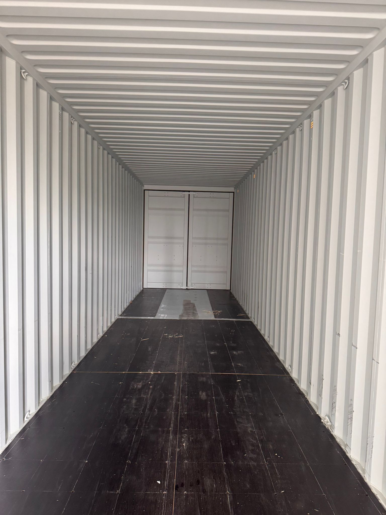 Interior of a new 40ft one-trip shipping container — pristine white walls and dark hardwood floor, Lyonheart Containers Ontario