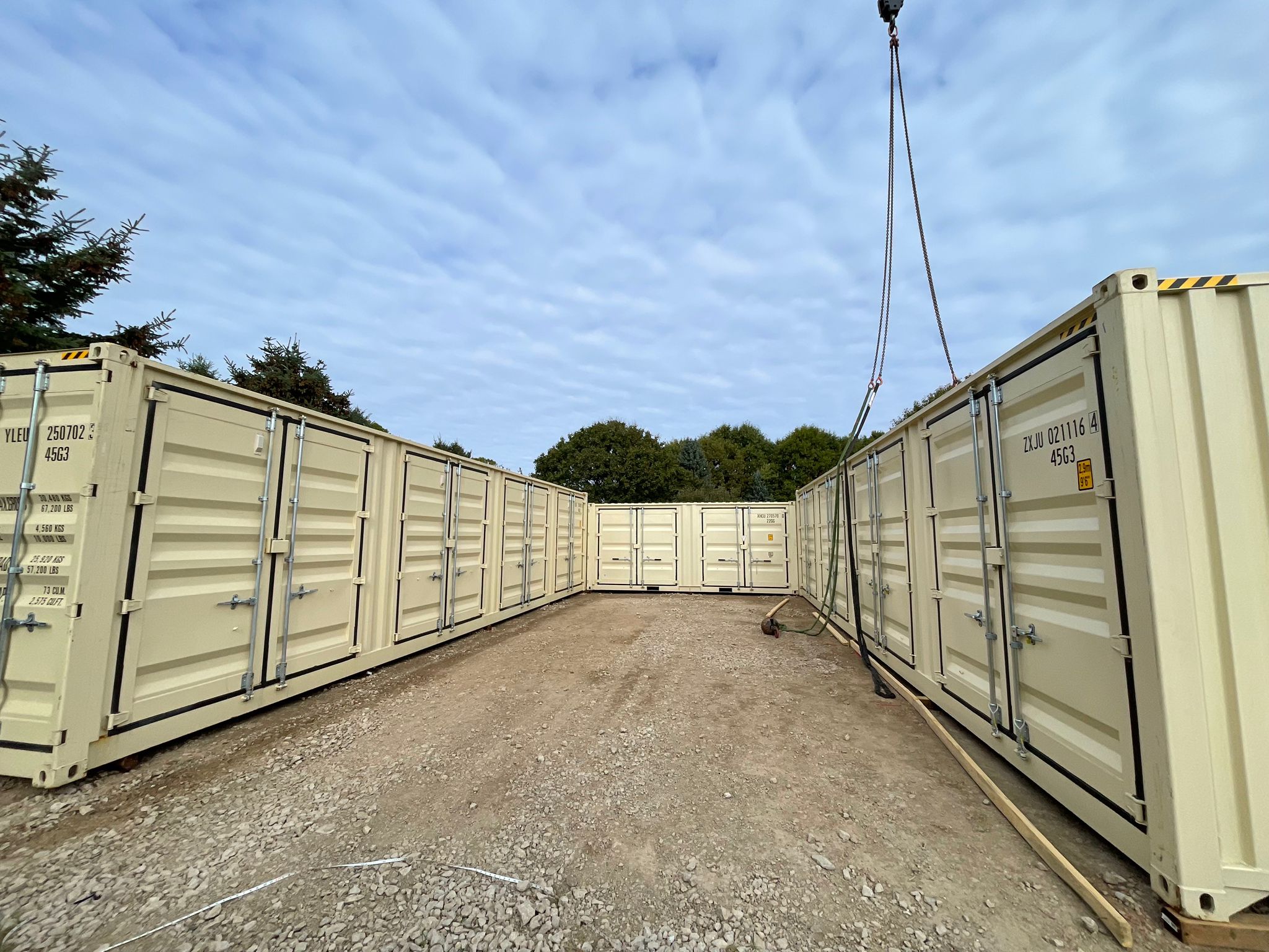 Multi-container compound installation by Lyonheart Containers — crane placing containers at rural Ontario property